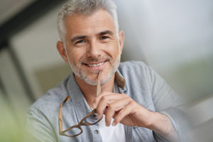 A man takes off his glasses and smiles after learning about Splendid Dental Care in Bellaire