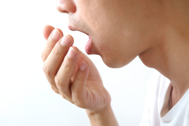 causes of bad breath (1) person checking their breath to avoid causes of bad breath