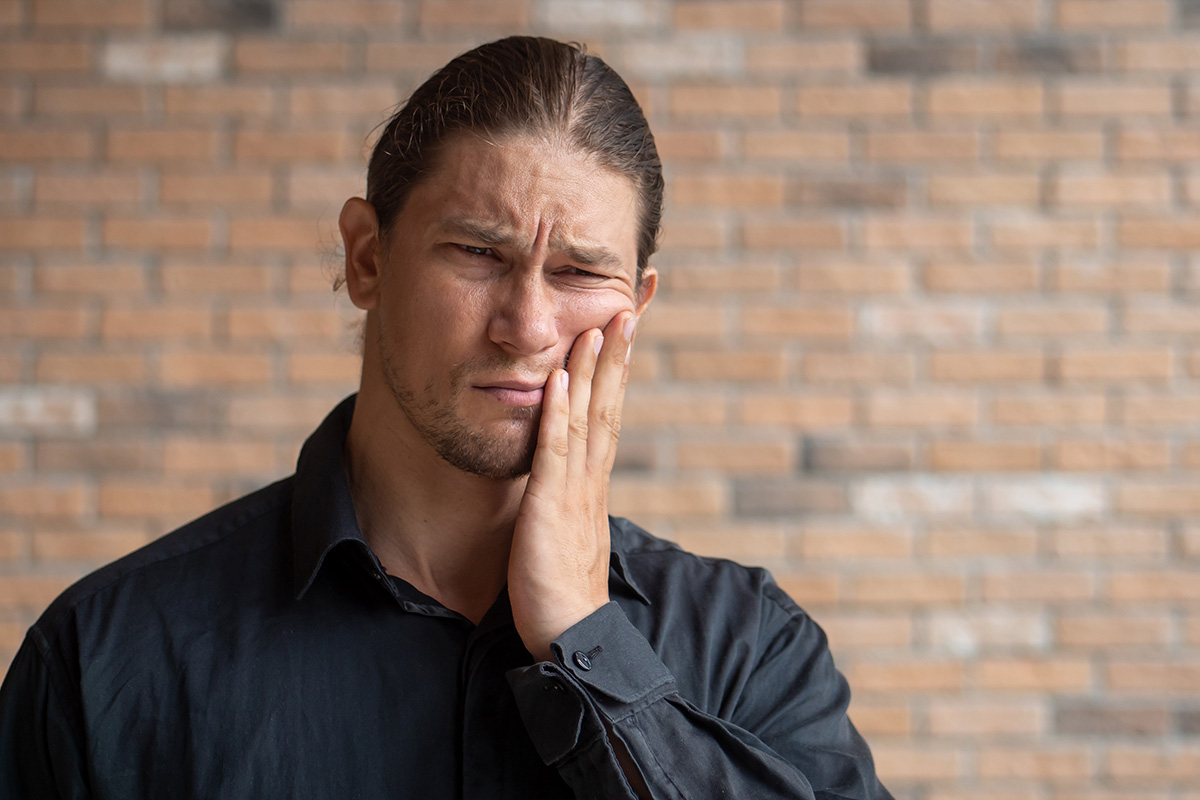 man holding his cheek in pain wondering How Does Tooth Decay Develop