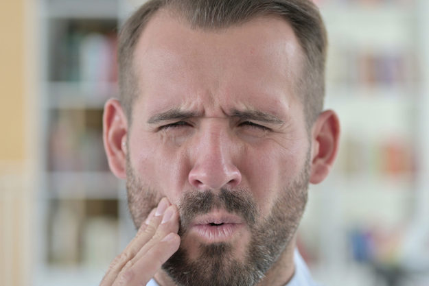 common dental problems (1) man wincing in pain from Common Dental Problems
