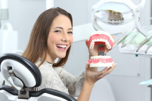 a woman with Impacted Teeth holding a mouth model